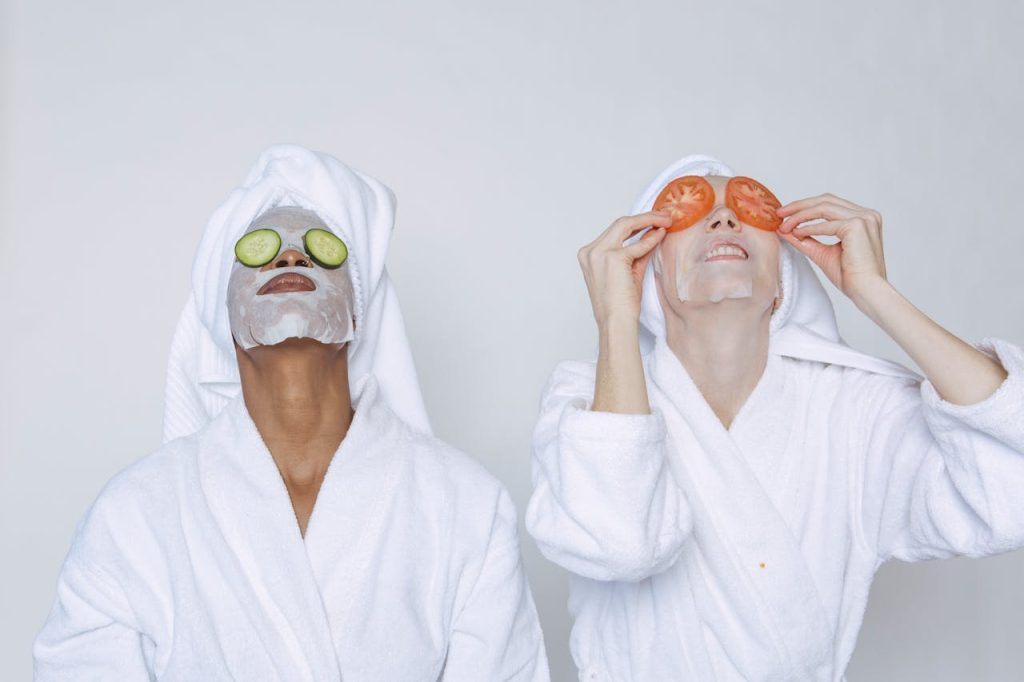 diverse-women-doing-beauty-morning-routine-7479814 Young multiethnic females wearing bathrobes and towels moisturizing face with masks and slices of tomatoes and cucumbers against white background